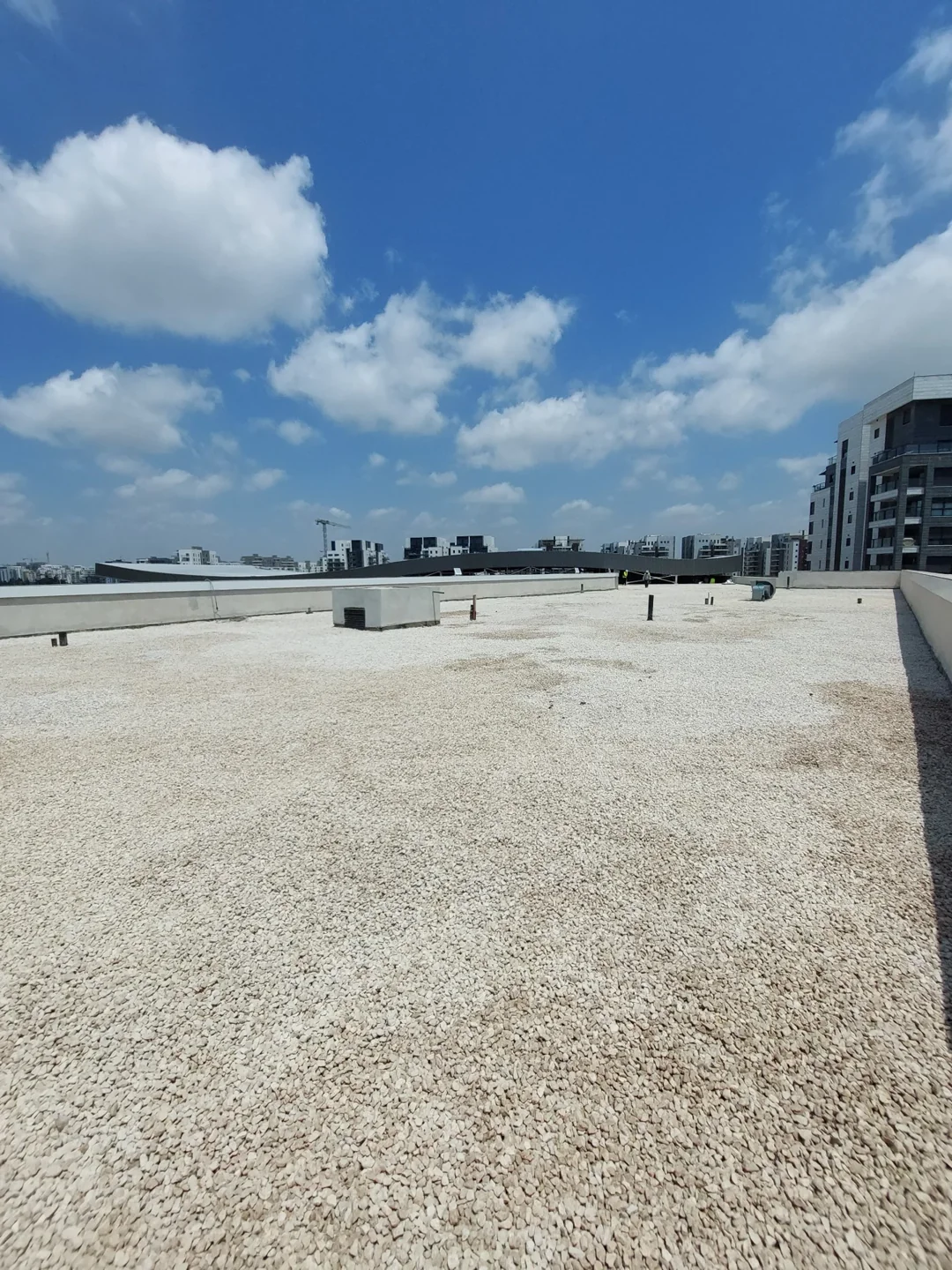 גג עם שכבת חצץ בהירה ומערכות על הגג